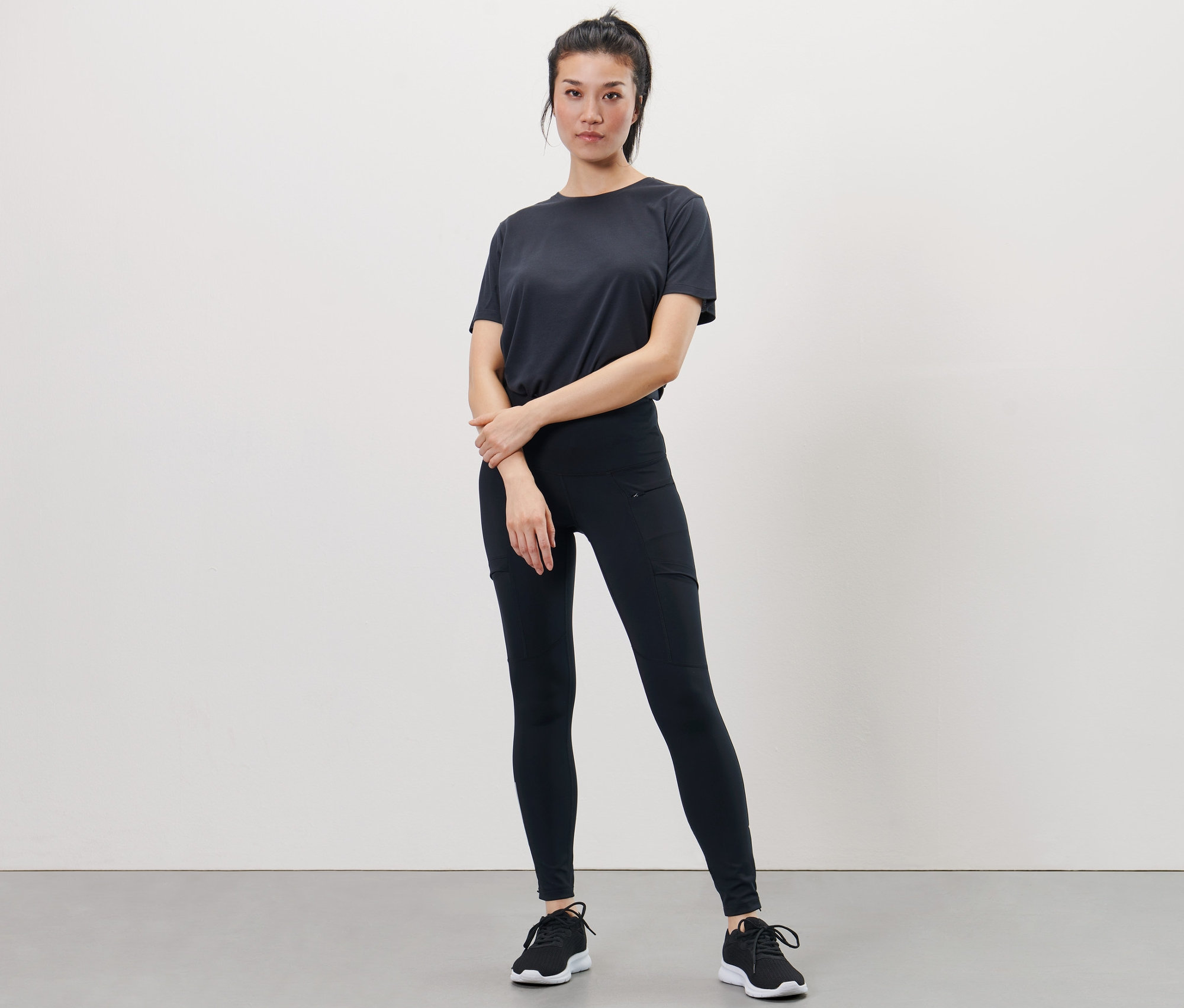 Frau posiert in schwarzem T-Shirt und Performance-Lauftight.