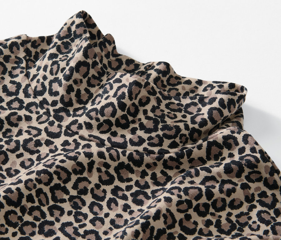 Detailansicht eines bedruckten Blusenshirts mit Stehkragen im Leopardenmuster.