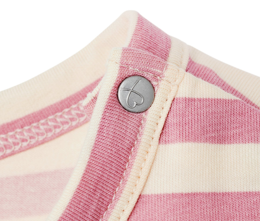 Detailansicht eines Baby-Jerseykleides mit rosa- und cremefarbenen Streifen und einem silberfarbenen Knopf in Herzform.
