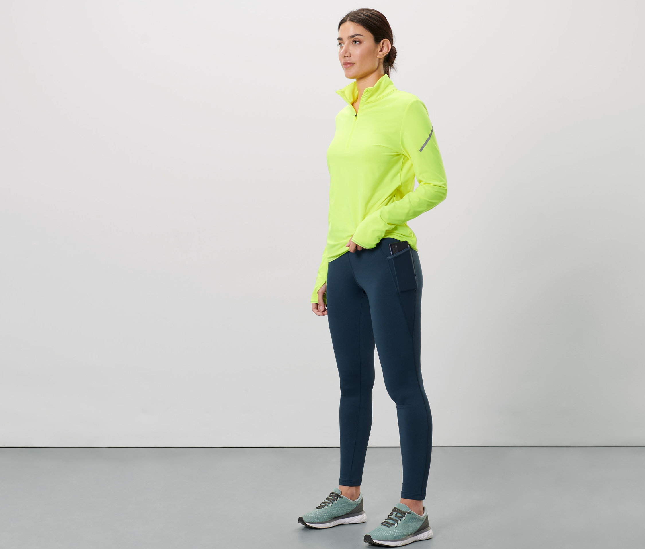 Frau trägt eine dunkelblaue Thermo-Lauftight und ein neongelbes Oberteil.