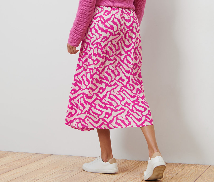 Frau trägt pinken Pullover und bedruckten Midi-Rock, pink.