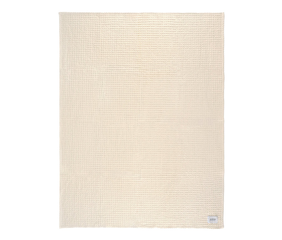 Eine cremefarbene SCHÖNER WOHNEN Wohndecke mit Waffelstruktur.