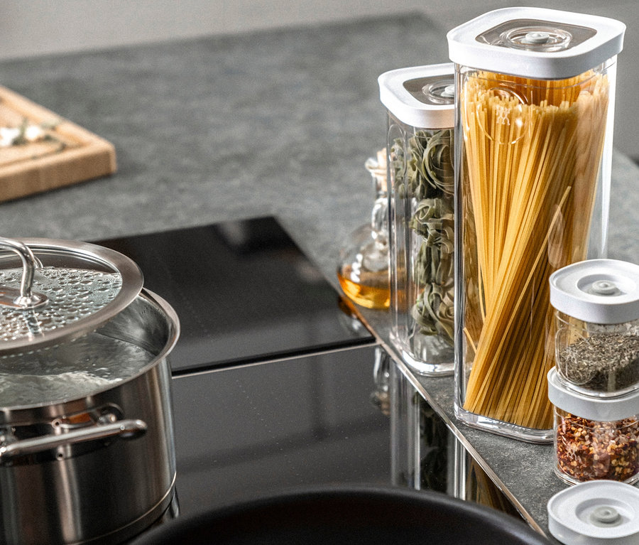 Auf dem Herd stehen ein Topf mit kochendem Wasser, eine Pfanne mit Soße und ein ZWILLING FRESH & SAVE CUBE, Vakuum-Box-Set, S, 6-teilig.