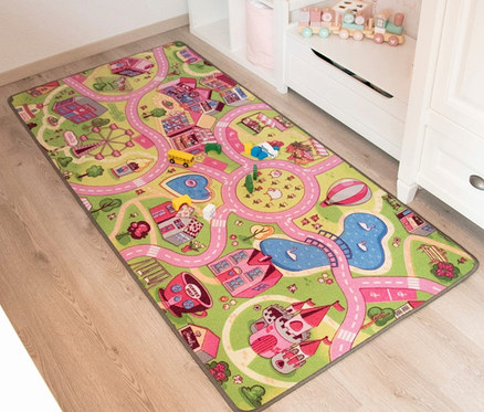 Ein Spielteppich »Sweet City« liegt auf dem Boden neben weißen Möbeln.
