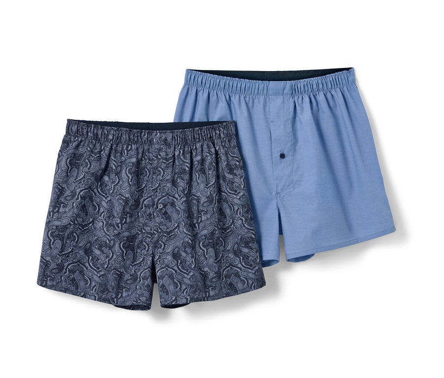 Zwei Webboxershorts, eine blau mit Paisleymuster, eine hellblau.