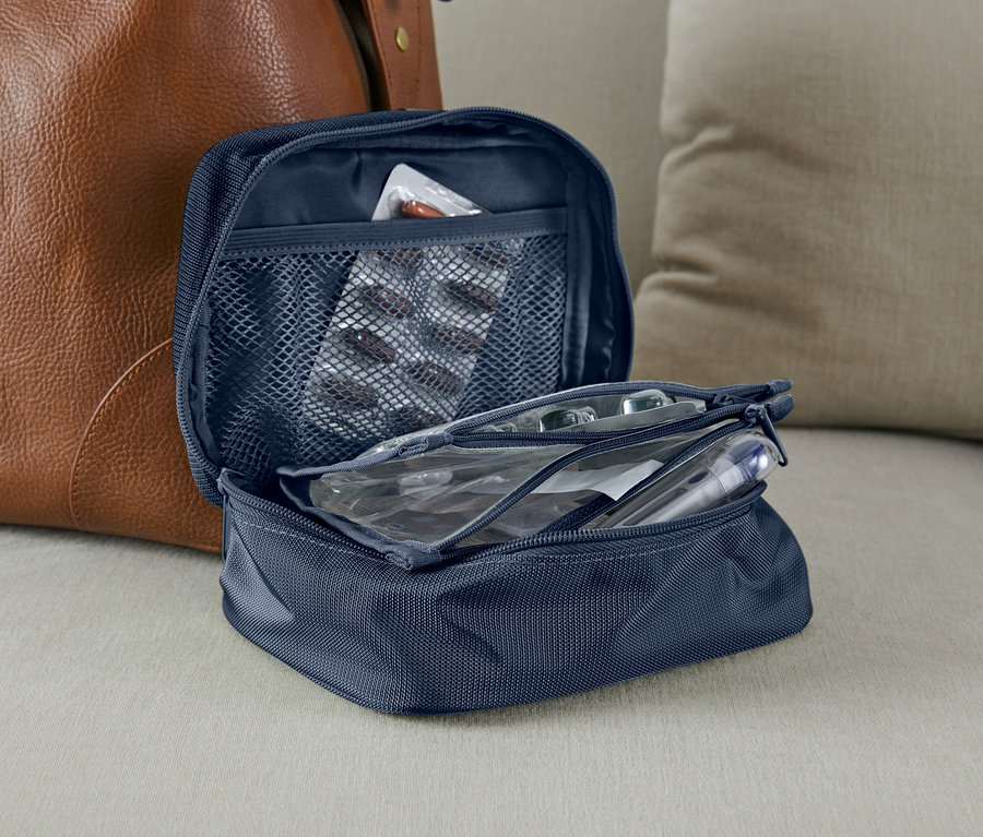 Offene blaue Medikamententasche neben einer braunen Ledertasche.