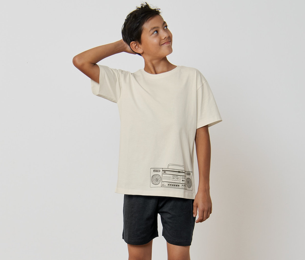 Junge im Kinder-Pyjama mit Radio-Muster steht barfuß im Raum.