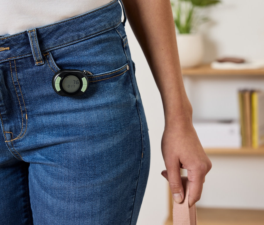 Schwarzer Schrittzähler an der Vordertasche einer blauen Jeans befestigt.