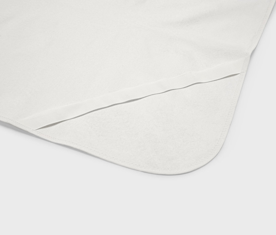 Nahaufnahme einer weißen Babydecke mit abgerundeten Ecken und einem elastischen Saum.