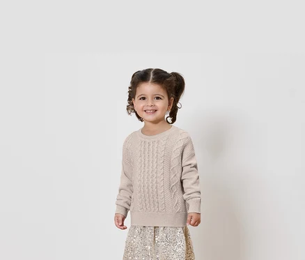 Lächelndes kleines Mädchen mit Zöpfen posiert in Pullover und Rock.