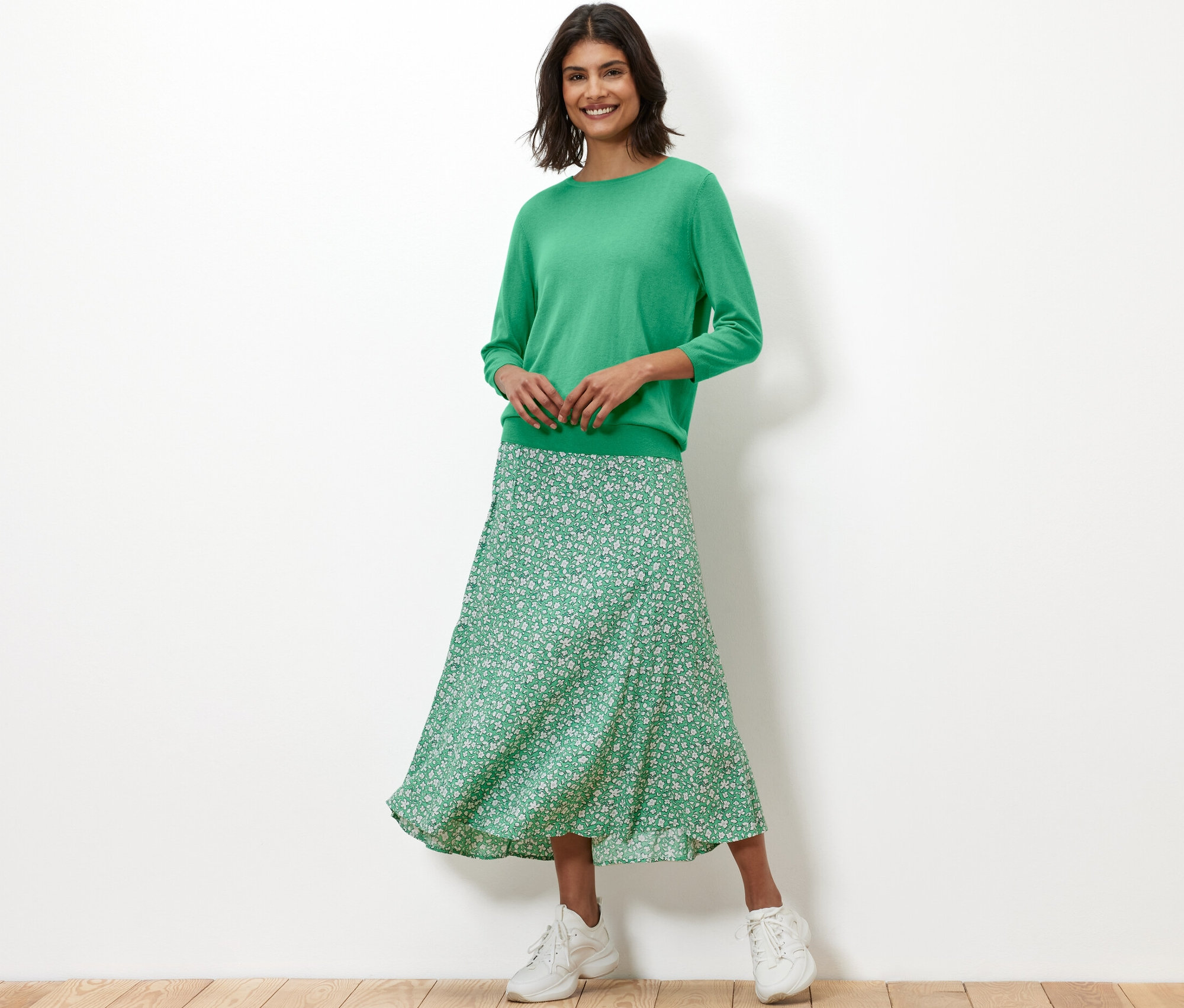 Frau trägt grünen Feinstrickpullover mit Seide und geblümten Rock.