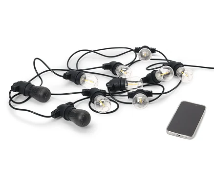 Eine schwarze LED-Outdoor-Lichterkette mit 2 Bluetooth®-Lautsprechern liegt neben einem Handy auf einem weißen Hintergrund.
