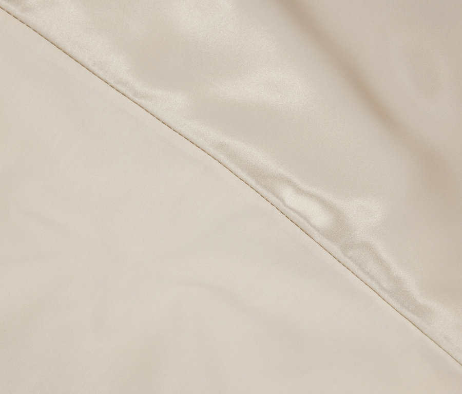 Detailaufnahme eines cremefarbenen Stoffes mit Naht.