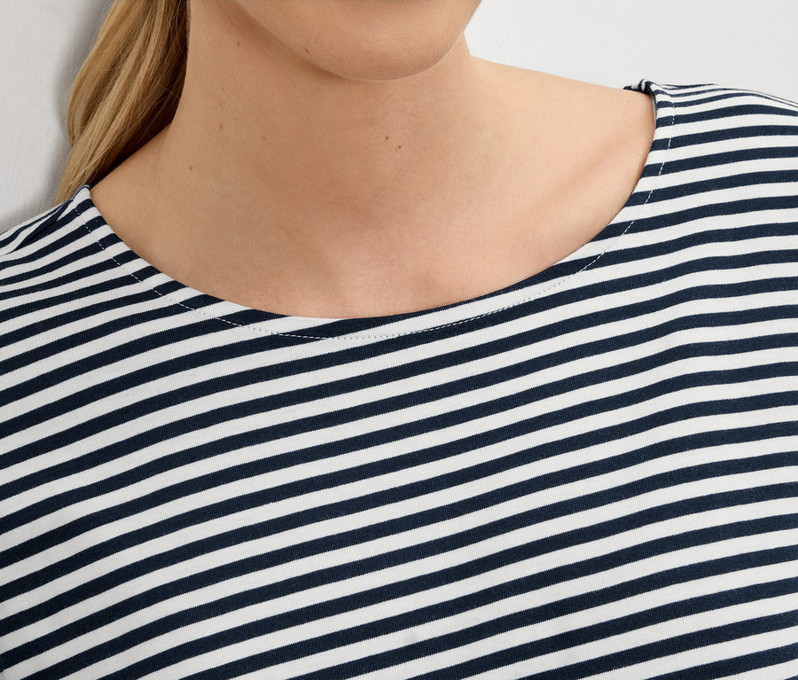 Nahaufnahme einer Frau, die ein blau-weiß gestreiftes Oberteil trägt.