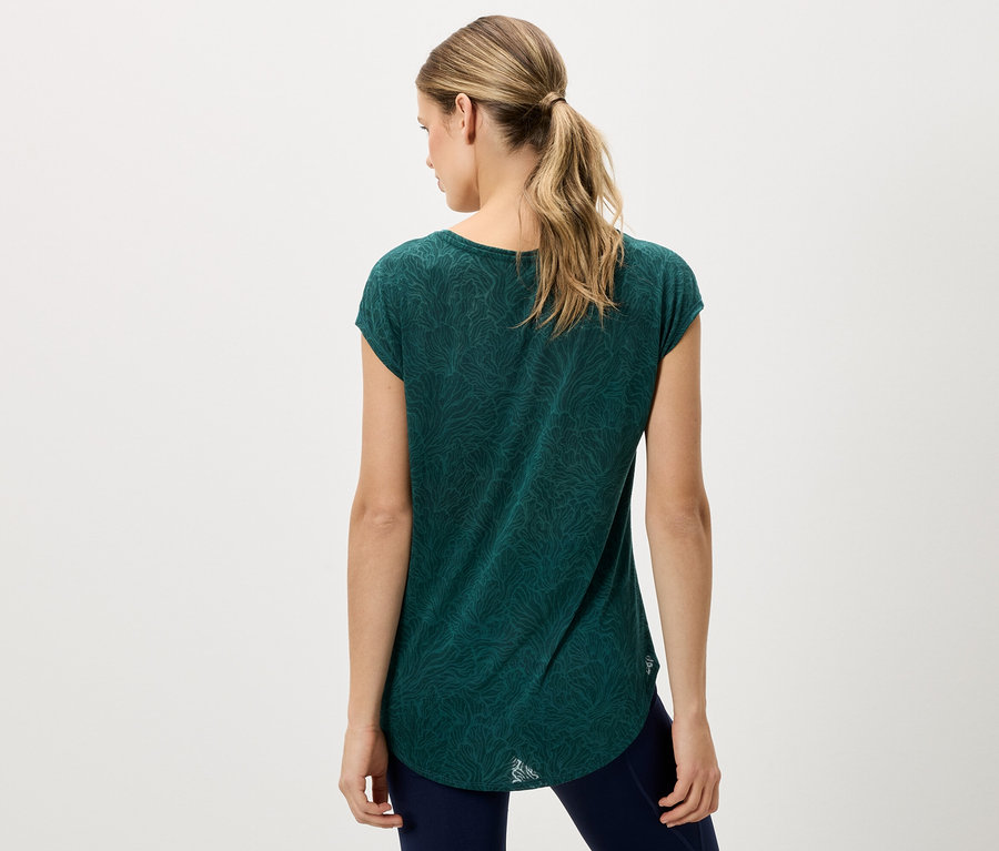 Rückansicht einer Frau mit blonden Haaren, die ein grünes T-Shirt und blaue Hosen trägt.