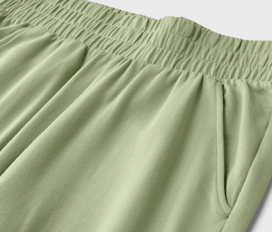 Nahaufnahme der Taille einer hellgrünen Hose mit Gummizug und einer Seitentasche.