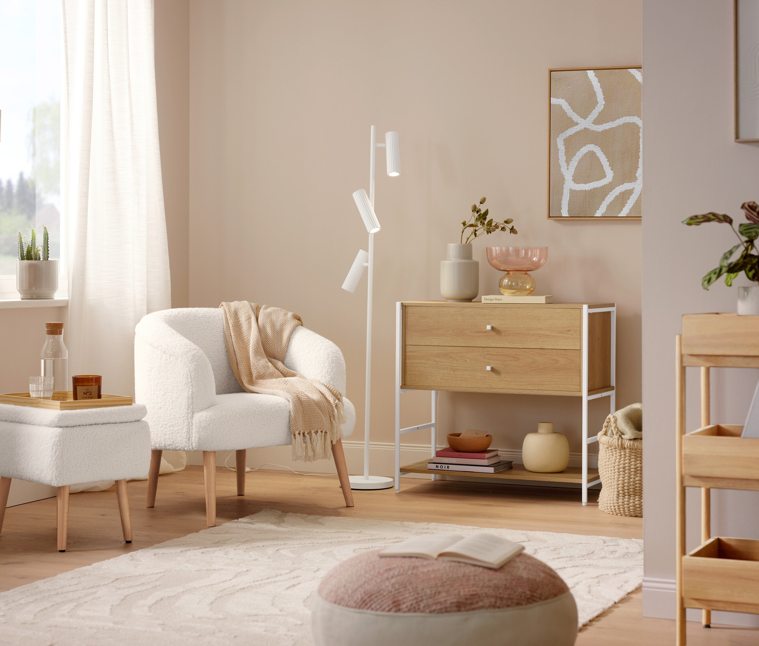 Ein Bouclé-Sessel mit Holzbeinen steht neben einer Trio Stehleuchte »Soka«. Ein grauer Teppich »Cosmo «Waves liegt auf dem Boden.