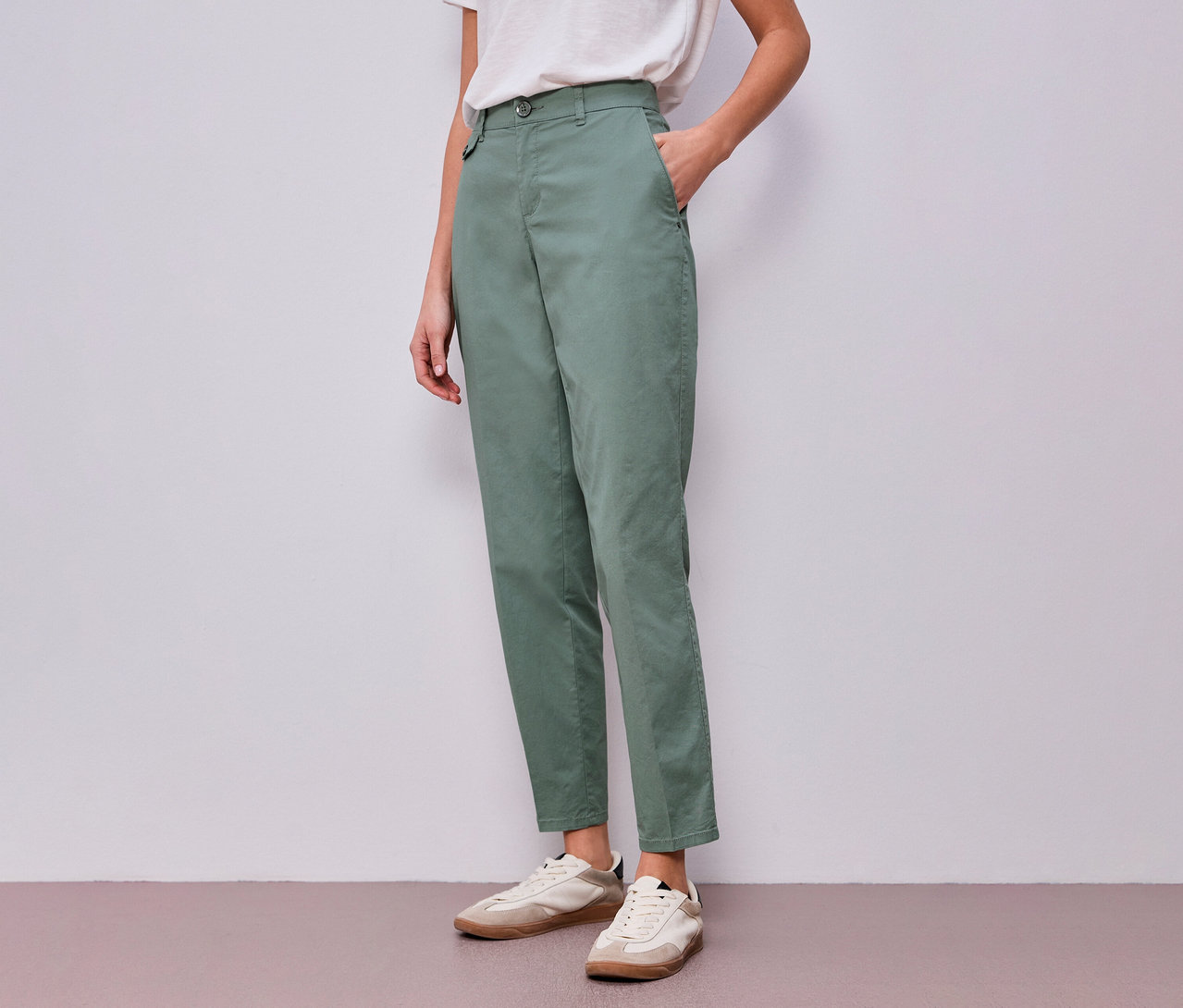 Frau mit Street One Chino in Mint und weißem T-Shirt, eine Hand in der Hosentasche.