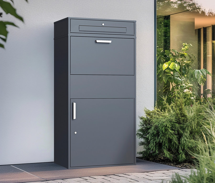 Graue Paketbox XXL an einer Wand neben Pflanzen.