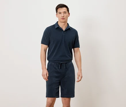Mann trägt ein marineblaues Poloshirt und marineblaue Shorts.