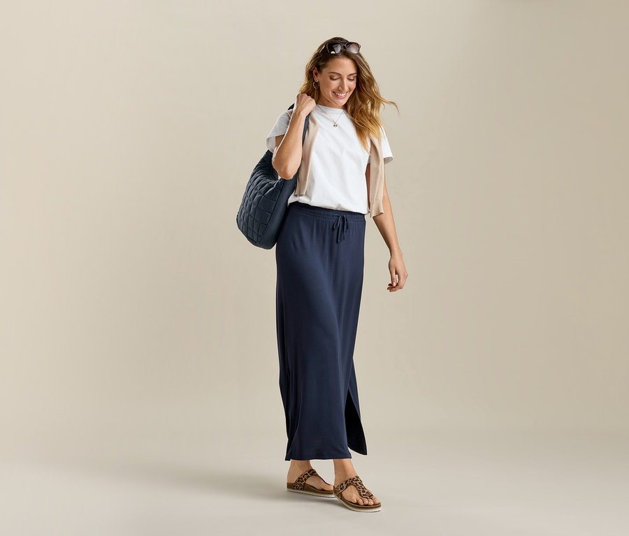 Frau mit Basic-T-Shirt, weiß, und langem Jerseyrock. Sie trägt eine Tasche über der Schulter.