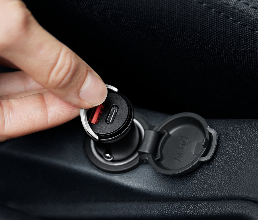 Hand schliesst einen schwarzen USB-C-Autoladegerät an.