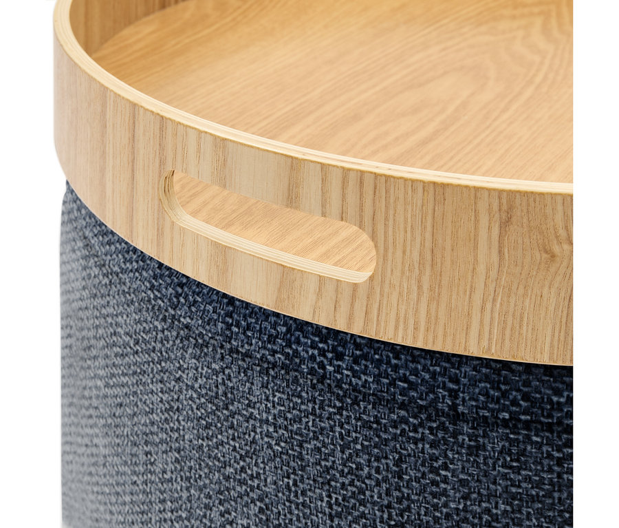 Rundes Möbelstück mit einer hellen Holztablettplatte und einem dunkelblauen, strukturierten Stoffunterteil. Die Holzplatte hat einen ausgeschnittenen Griff.