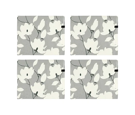 Vier graue, florale Tischsets der SCHÖNER WOHNEN Kollektion mit weißen Blumen und Blättern auf hellgrauem Hintergrund.