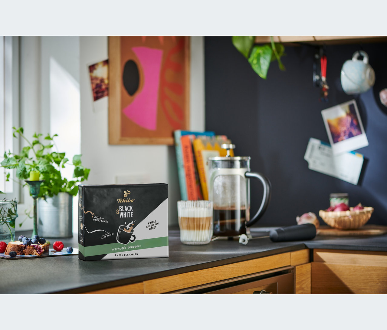 Eine Packung BLACK & WHITE - 2 x 250 g Gemahlen, eine French Press und ein Glas mit Kaffee stehen auf einer Küchentheke.
