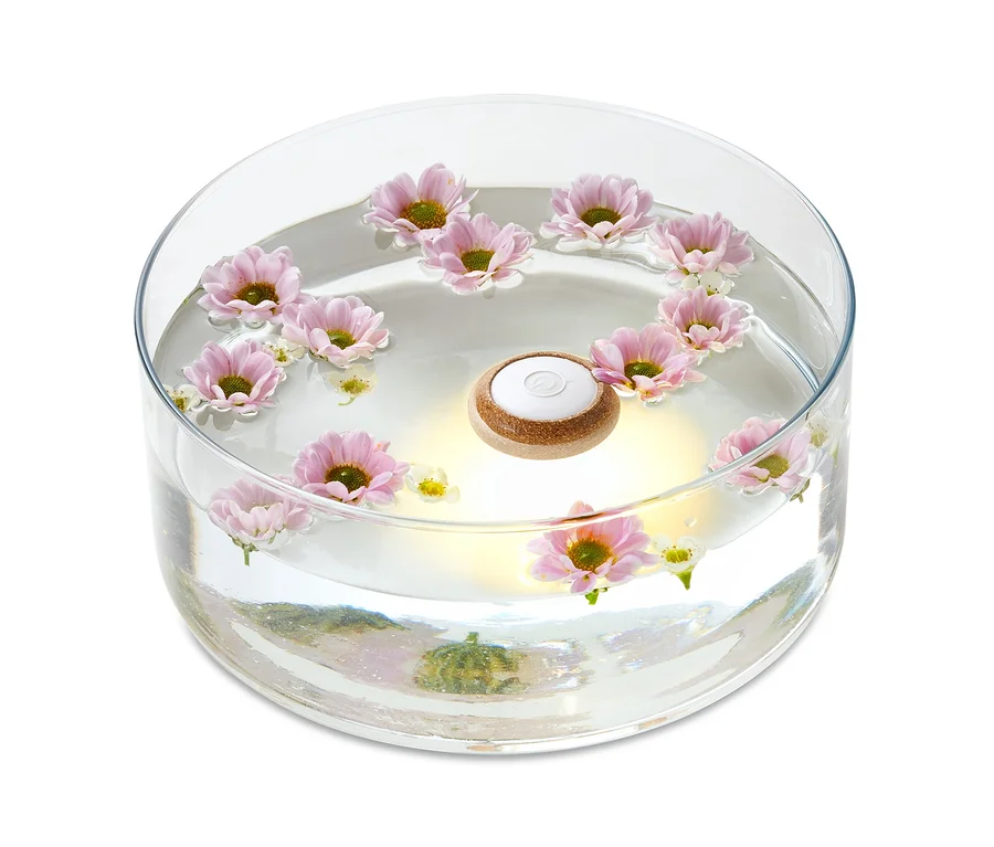 LED-Schwimmlicht in einer runden Glasvase mit rosa Blumen.
