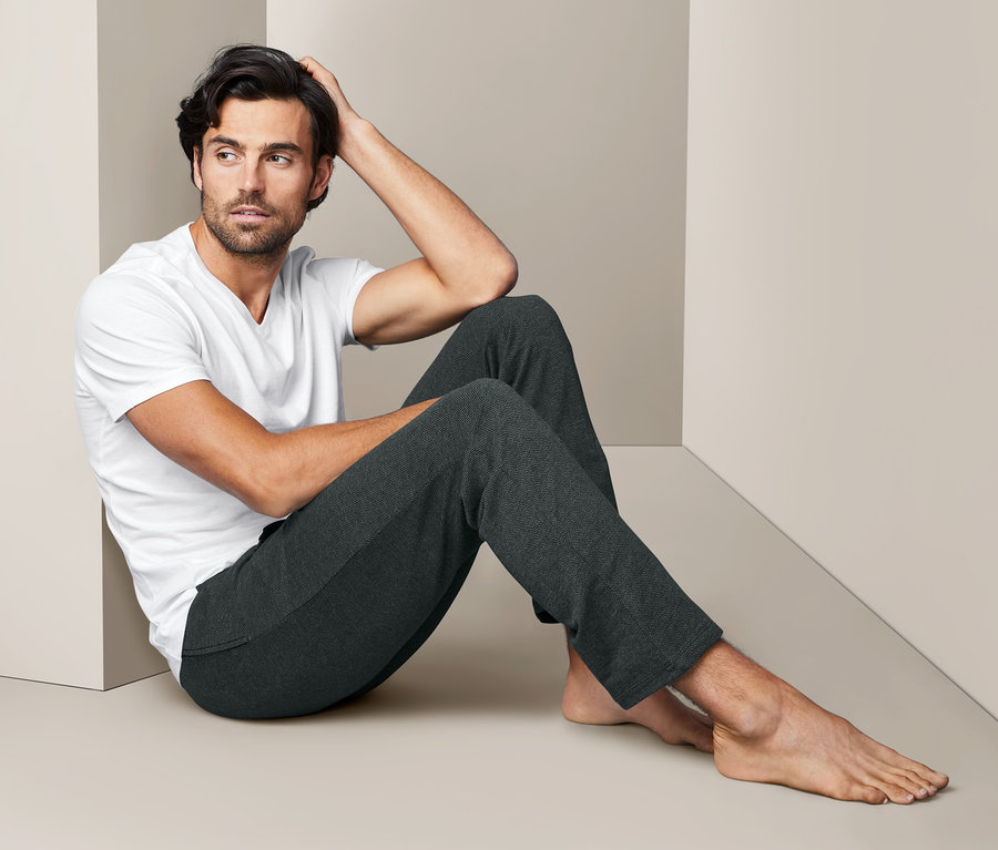 Mann sitzt auf dem Boden und trägt eine Homewear-Hose und ein T-Shirt.