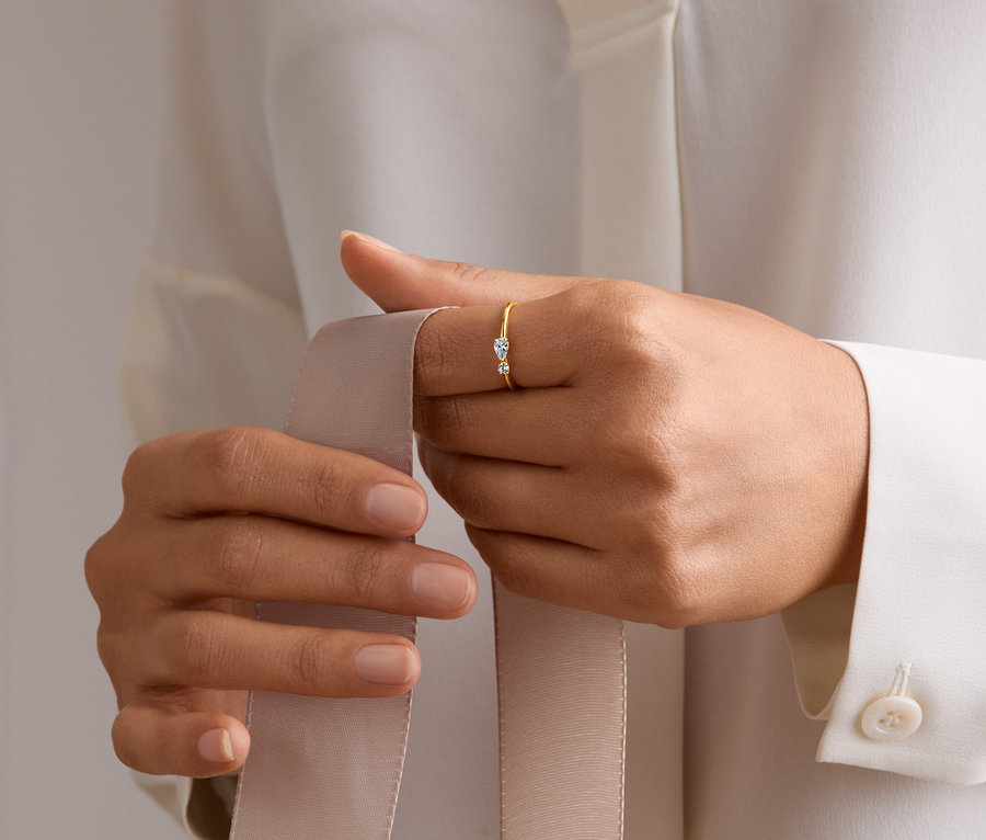 Eine Frau hält ein Band in der Hand und trägt einen Ring aus 585 Gold mit Zirkonia.