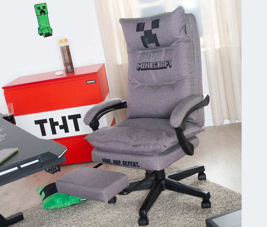Grauer roba Minecraft Gaming-Stuhl mit Fußstütze steht auf einem Teppich. Im Hintergrund befinden sich eine Truhe mit TNT-Motiv und Minecraft-Dekoration.