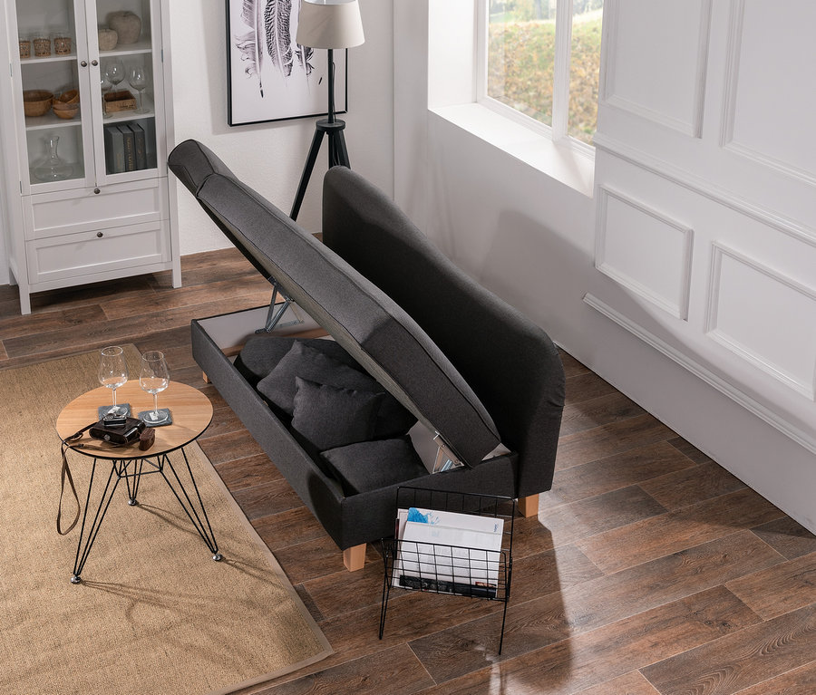 Graue Max-Winzer®-Recamiere »Saturn« mit Stauraum und Kissen teilweise geöffnet neben Tisch und Zeitschriftenregal.