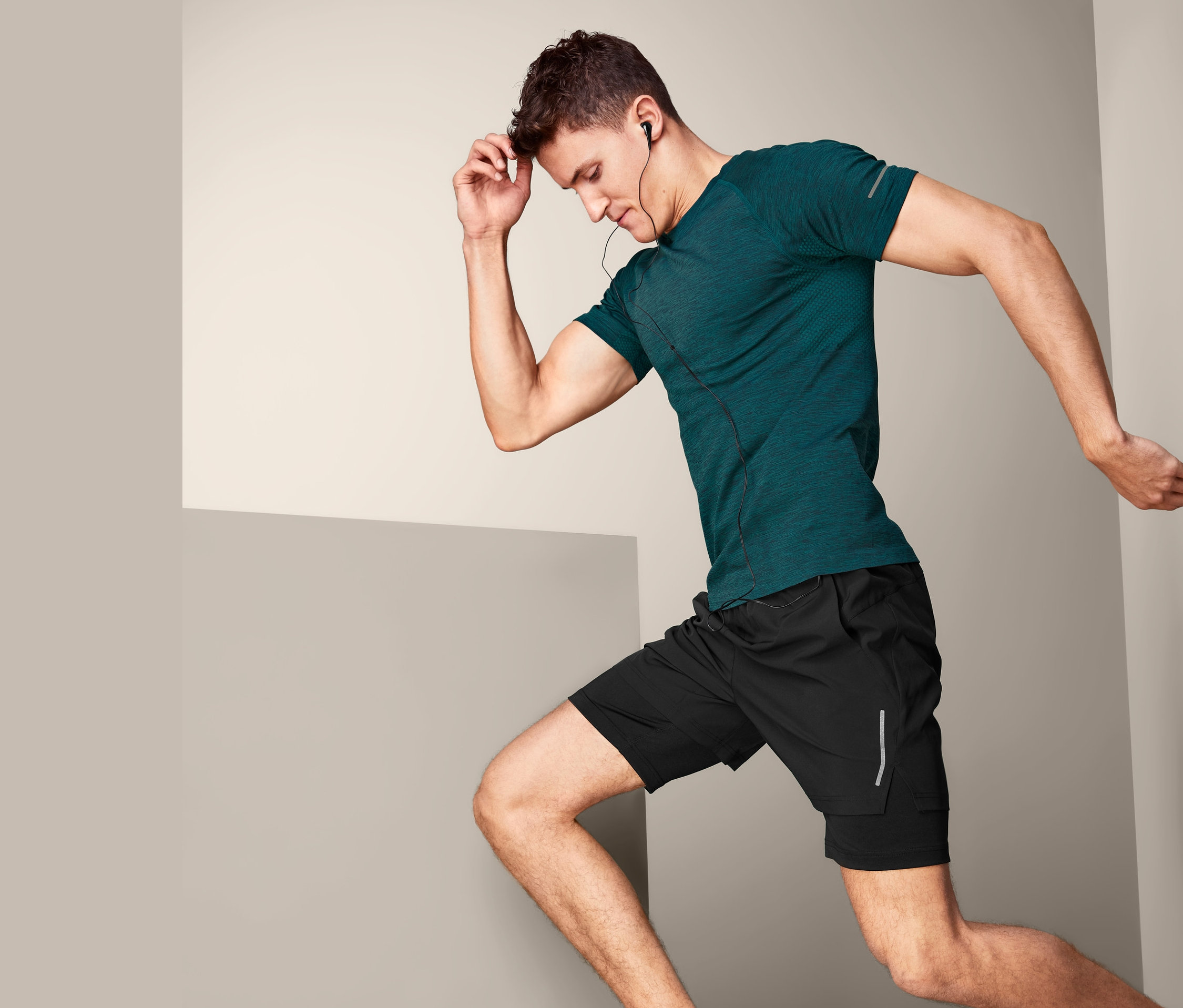 Mann in Bewegung trägt ein Klima-Tec-Funktionsshirt, schwarze Shorts und Turnschuhe.