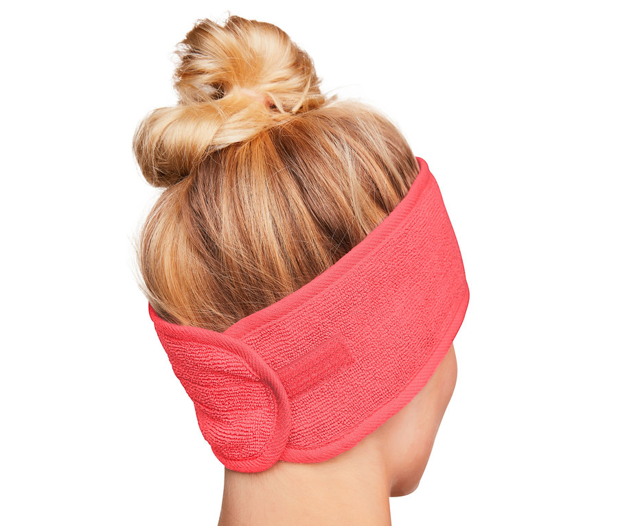 Rückansicht einer Frau mit blondem Haar im Dutt, die ein korallfarbenes 2 Kosmetik-Stirnband trägt.