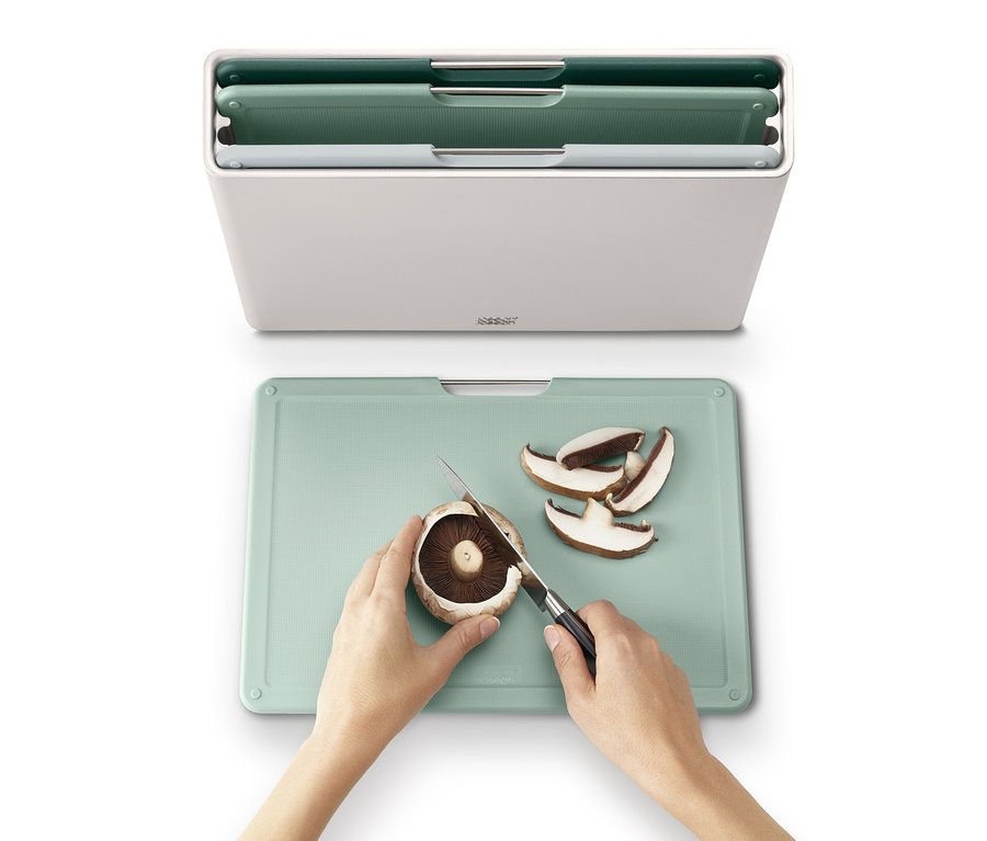 Eine Frau schneidet einen Pilz auf einem grünen Schneidebrett aus dem Joseph Joseph großes Schneidebrett-Set »Folio™«.