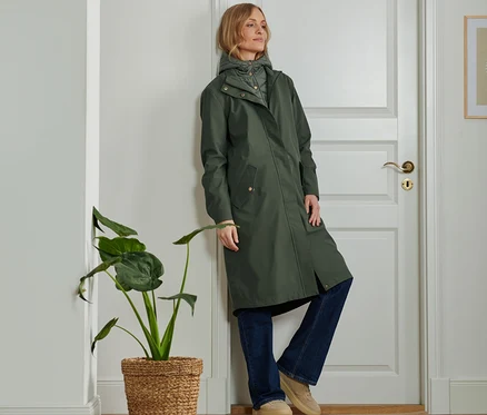 Frau lehnt an Tür und trägt einen 2-in-1-Outdoorparka.