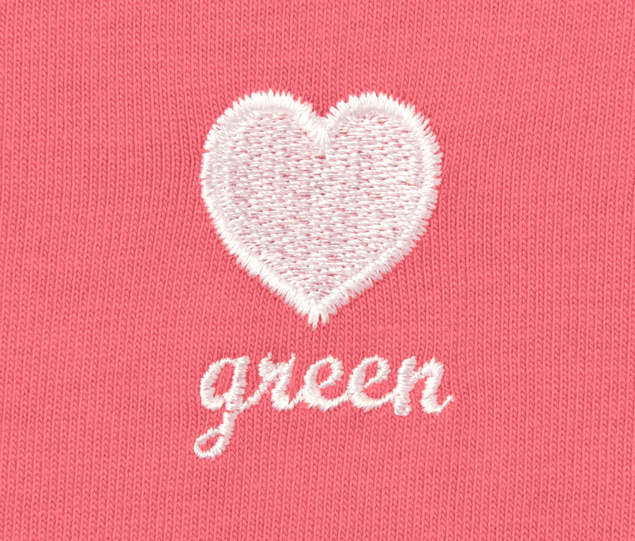 Detailansicht eines rosafarbenen Oversized-Shirts mit Stickerei eines weißen Herzens und dem Wort "green".