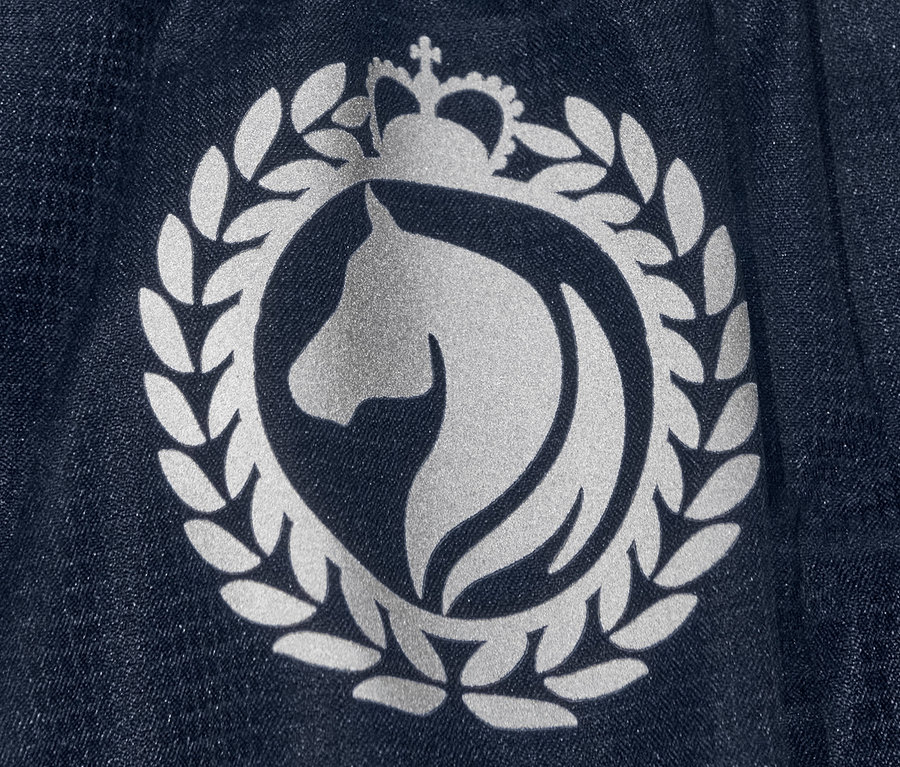 Detailaufnahme des Logos auf einer blauen Regen-Reithose mit recyceltem Material.