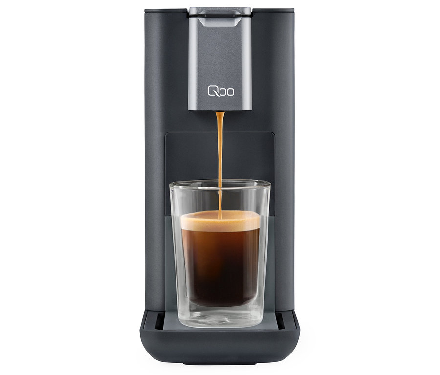 Kaffee läuft aus Qbo ESSENTIAL Dark Stone Kaffeemaschine in ein Glas.