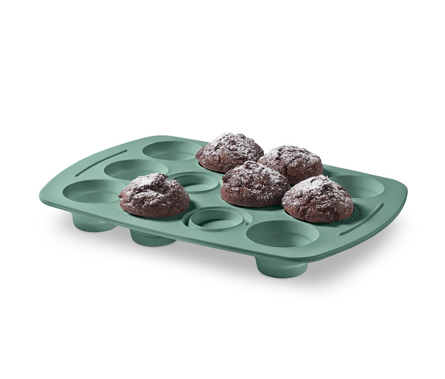 Sechs Muffins mit Puderzucker in einem Silikon-Muffinblech.