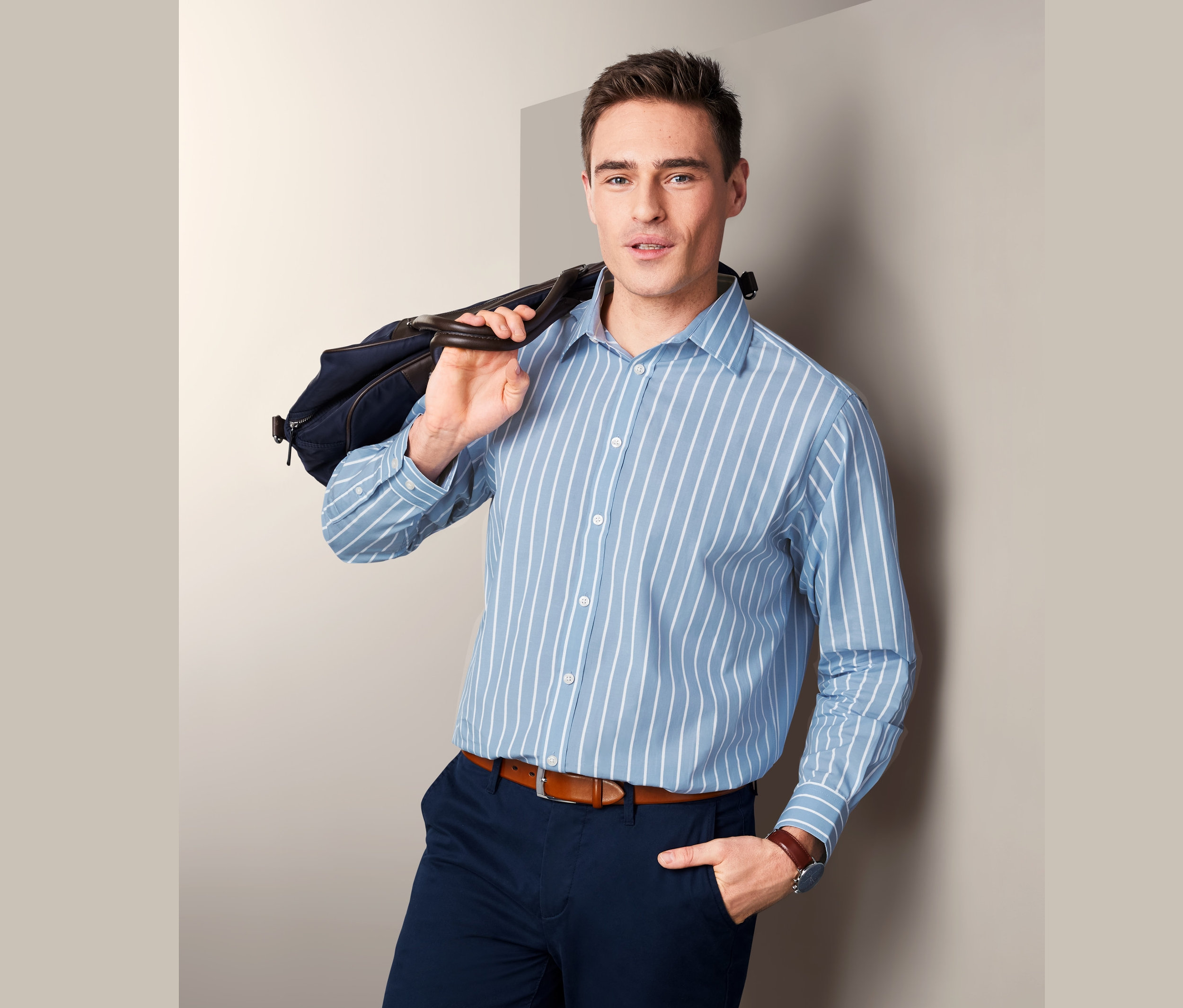 Mann mit Tasche über der Schulter trägt ein blaues Hemd mit Kent-Kragen, Comfort Fit.