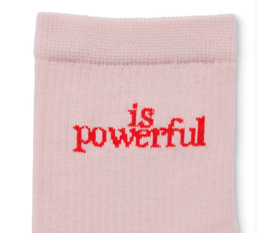 Detailaufnahme einer beigen Socke mit rotem "is powerful" Schriftzug. 2 Paar Statement-Socken.