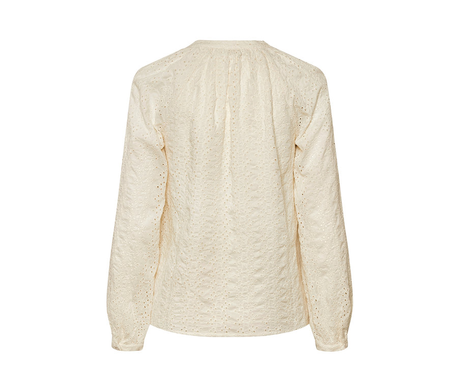 Detailaufnahme einer hellbeigen Bluse mit Lochstickerei.