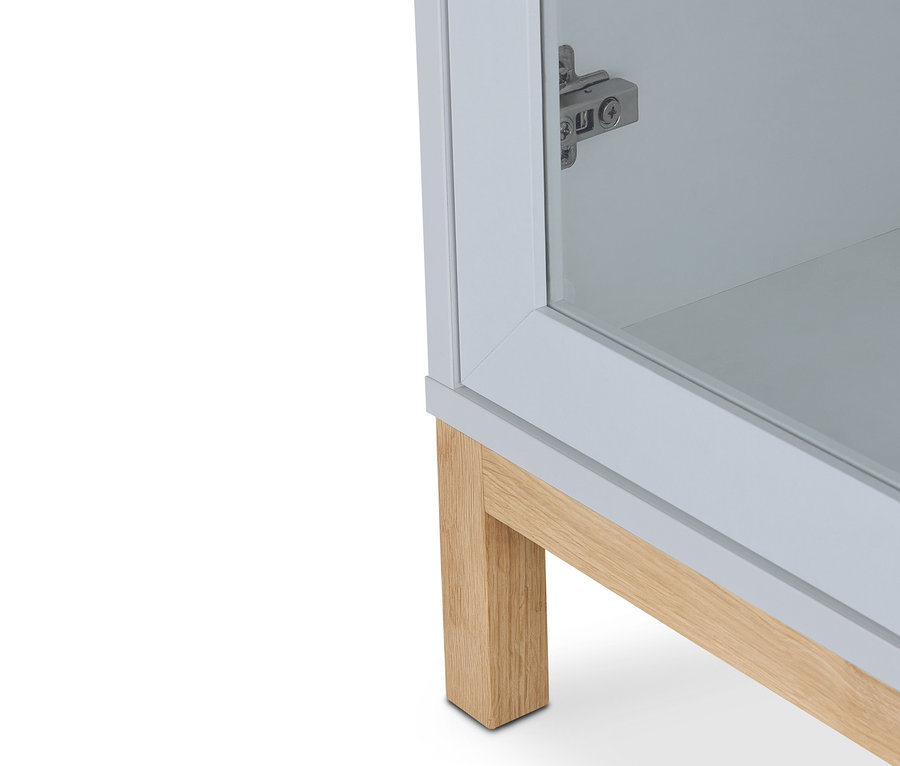 Detail einer grauen Vitrine »Eklund« mit 2 Türen und hellen Holzfüßen.