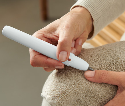 Frau benutzt ein Maniküre- und Pediküregerät auf einem Fingernagel.