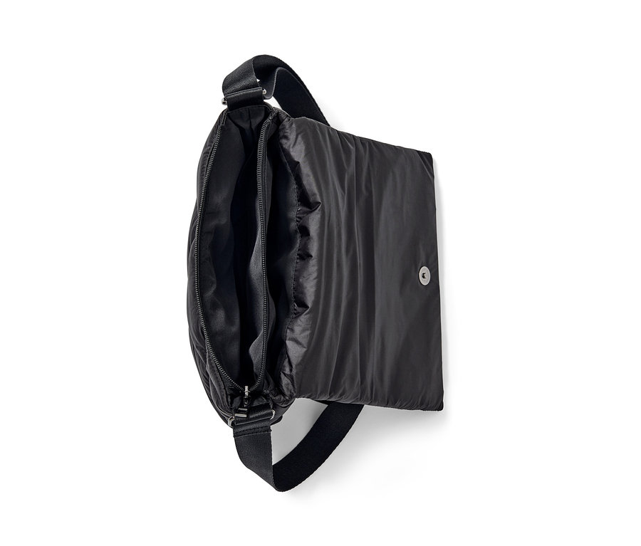 Eine geöffnete, gesteppte, schwarze Umhängetasche zeigt das Reißverschlussfach.