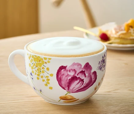 Eine Milchkaffeeschale mit Blumenmuster auf einem Tisch.
