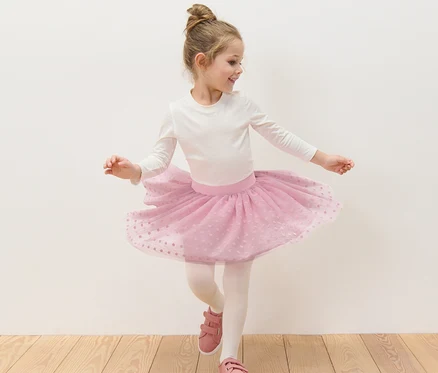 Mädchen tanzt in weißem Oberteil und rosa Kinder-Tüllrock.